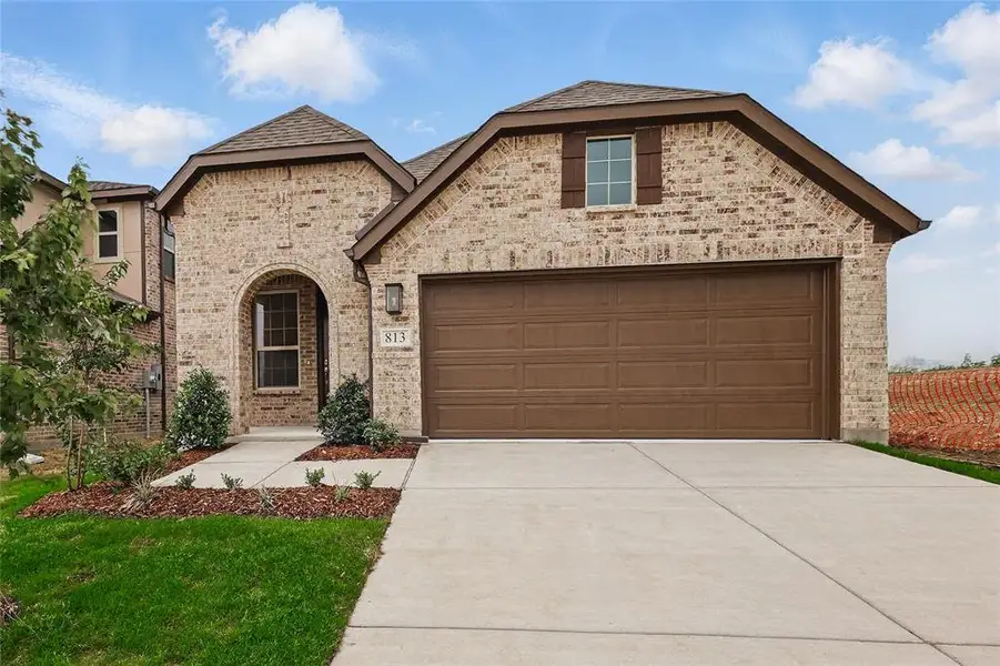 French country style house featuring brick siding, driveway, and roof with shingles