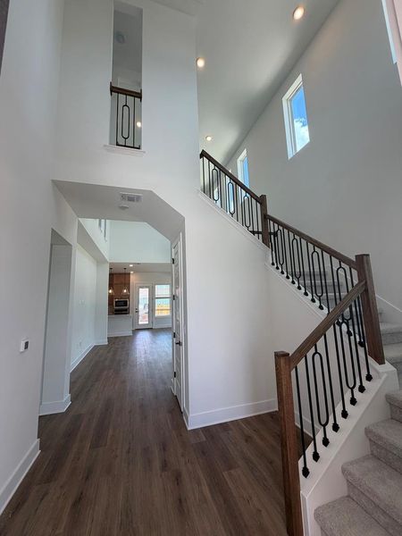 A grand entrance with high ceilings, warm wood flooring, and a contemporary staircase welcomes all. A grand entrance with high ceilings, warm wood flooring, and a contemporary staircase welcomes all.