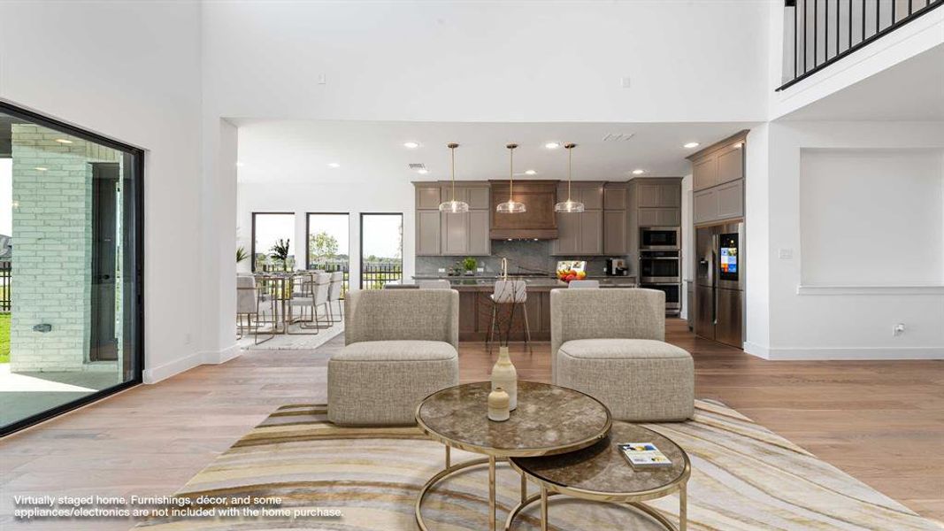 Living room with a towering ceiling and light hardwood / wood-style flooring