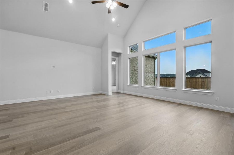 Spare room with a ceiling fan, high vaulted ceiling, baseboards, and light wood-style floors Spare room with a ceiling fan, high vaulted ceiling, baseboards, and light wood-style floors