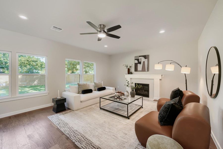 Naturally illuminated living space features rich hardwood flooring and a cozy fireplace with a mantle. Naturally illuminated living space features rich hardwood flooring and a cozy fireplace with a mantle.