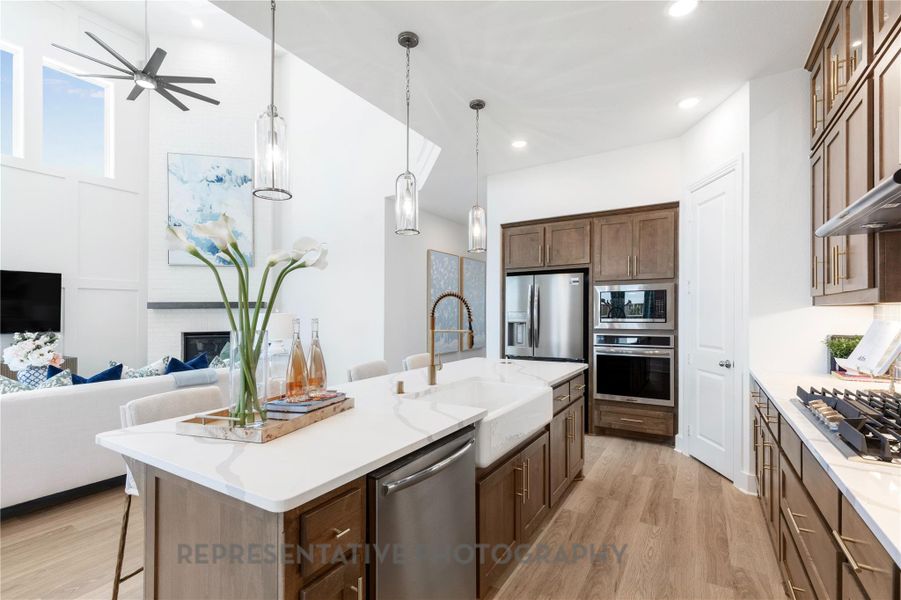 Kitchen featuring stainless steel appliances, open floor plan, a breakfast bar area, an island with sink, and light wood-type flooring
