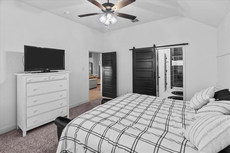 Carpeted bedroom featuring a barn door, baseboards, visible vents, and vaulted ceiling