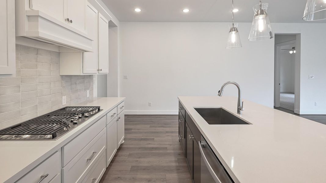 Kitchen with white cabinets, recessed lighting, decorative light fixtures, dark wood finished floors, and under cabinet range hood Kitchen with white cabinets, recessed lighting, decorative light fixtures, dark wood finished floors, and under cabinet range hood