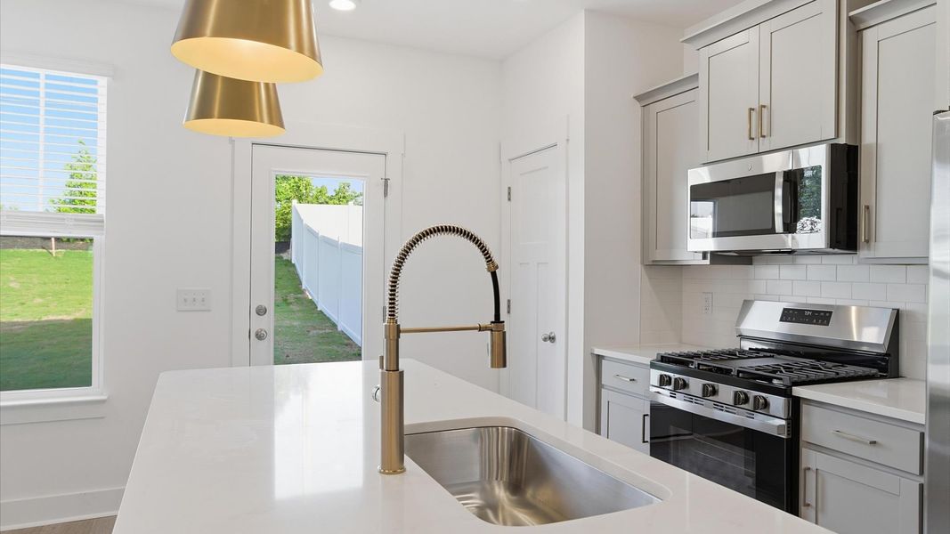 Tasteful design meets functional luxury in this kitchen with a center island and modern pendant lighting