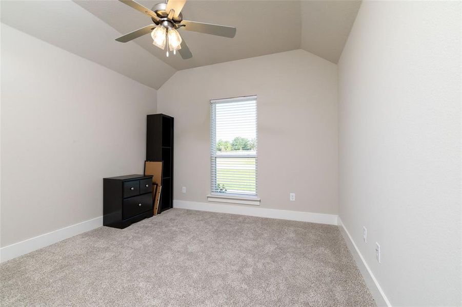 Unfurnished bedroom featuring vaulted ceiling, carpet, and a ceiling fan