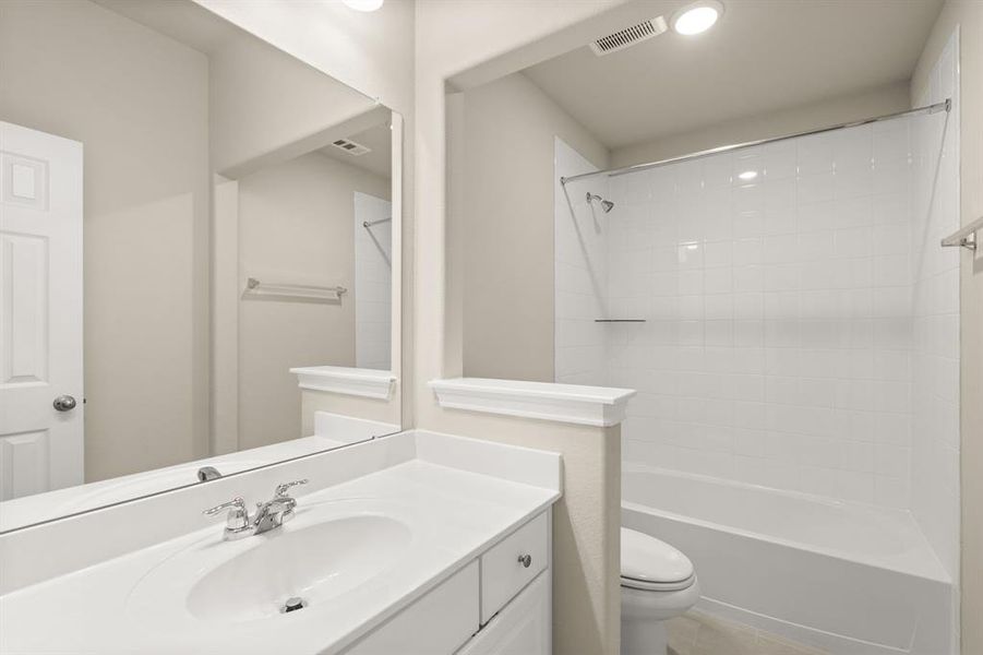 The secondary bath features tile flooring, white cabinetry and light countertops and a shower/tub combo. Perfect for accommodating any visiting family and friends.