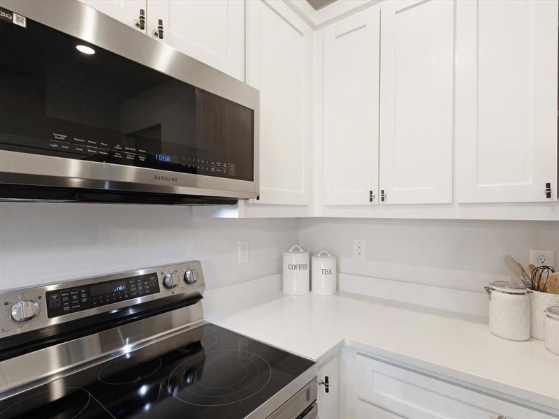 Kitchen with white cabinetry and appliances with stainless steel finishes