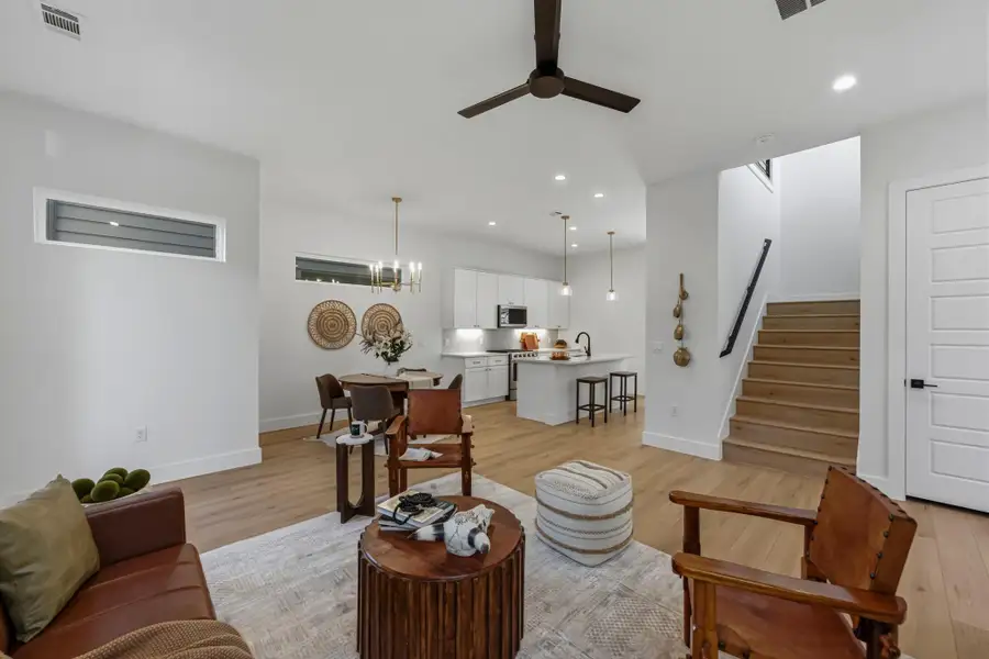 Living area featuring a ceiling fan, light wood-style floors, and suspended lighting