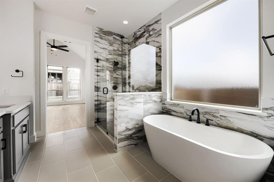 Contemporary bathroom featuring a freestanding soaking tub, expansive frosted window, and a walk-in shower with marble-finish tile Contemporary bathroom featuring a freestanding soaking tub, expansive frosted window, and a walk-in shower with marble-finish tile