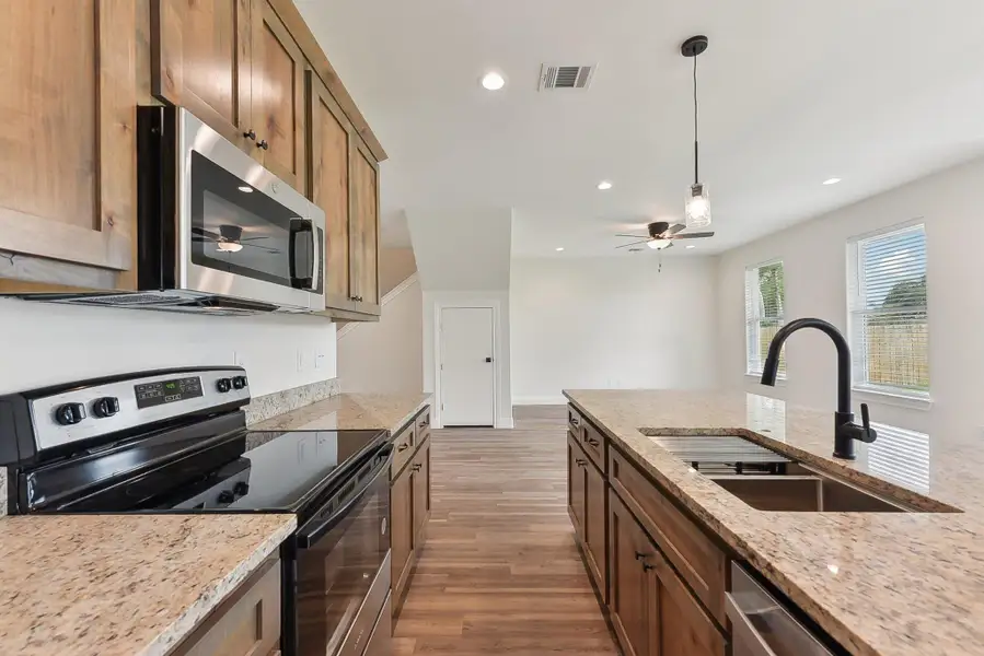 Kitchen with wood style floors, a sink, ceiling fan, stainless steel appliances, and visible vents