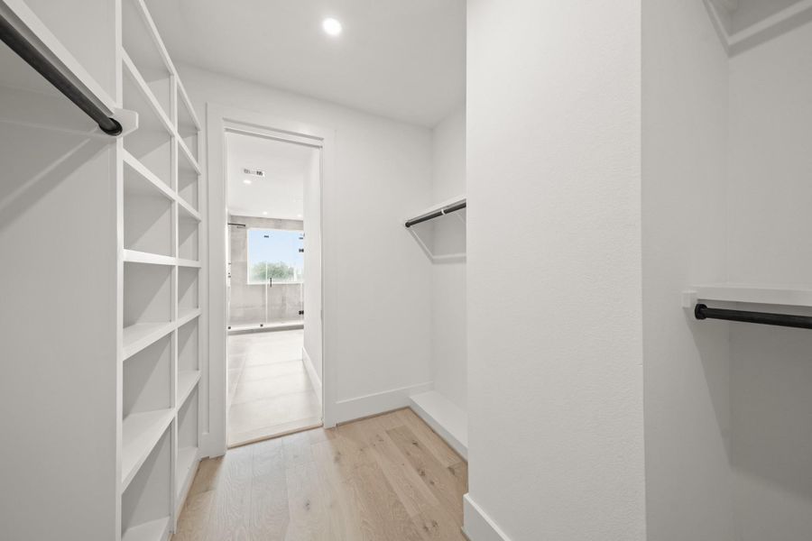 Another view of the primary closet highlights the hardwood floors, high ceilings which provides ample storage for clothing, shoes and accessories. The clean, modern design allows for organized storage and easy access throughout.