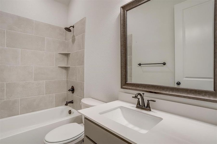 Full bathroom featuring tiled shower / bath, vanity, and toilet