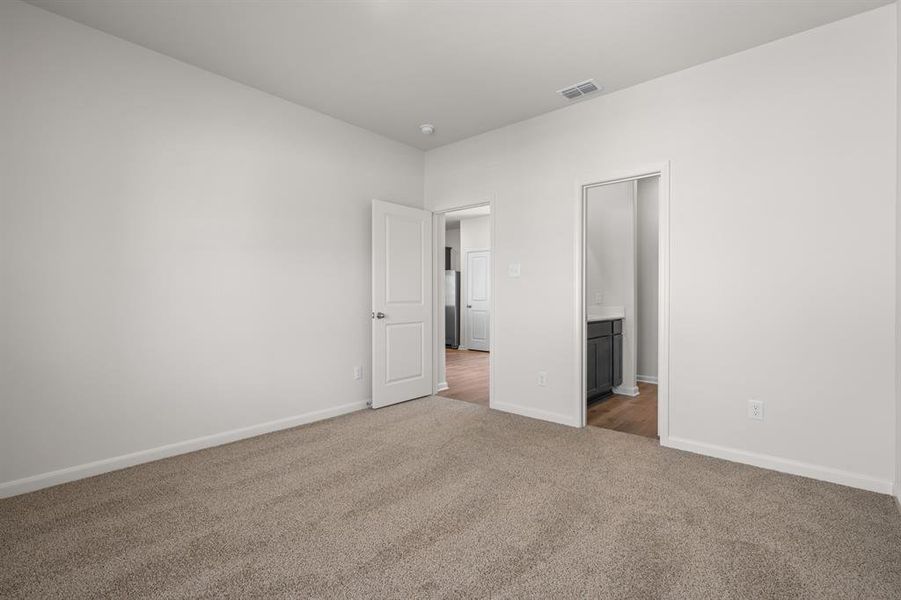 Unfurnished bedroom with ensuite bathroom and carpet