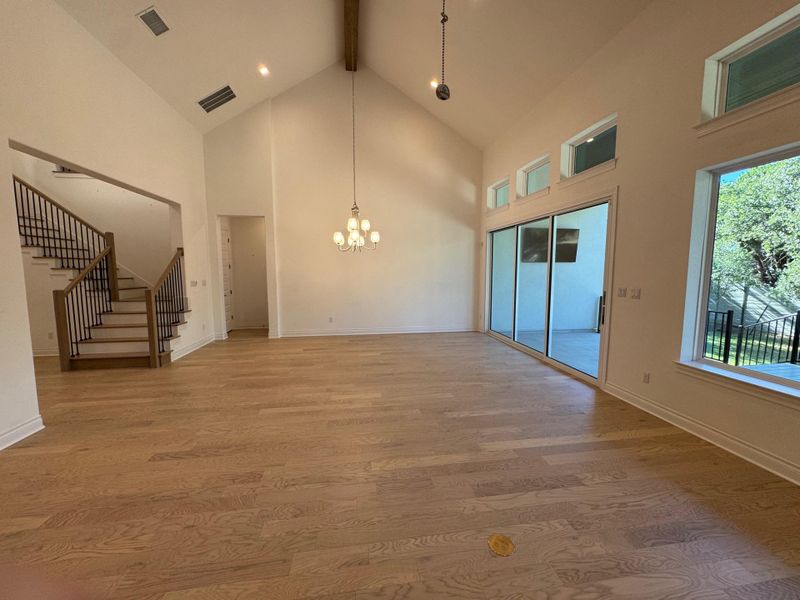 Open concept dinning room with chandelier, wood floors and soaring ceilings.