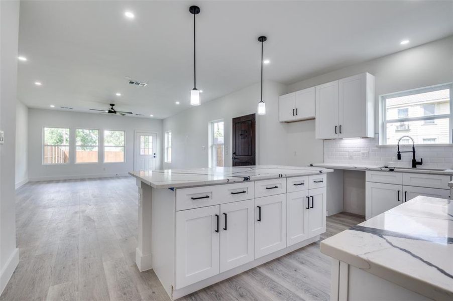Kitchen featuring light wood finished floors, ceiling fan, light stone countertops, white cabinets, and recessed lighting Kitchen featuring light wood finished floors, ceiling fan, light stone countertops, white cabinets, and recessed lighting