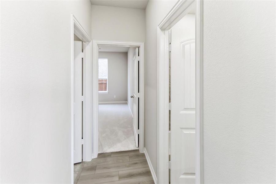 Hallway with light wood-type flooring and baseboards