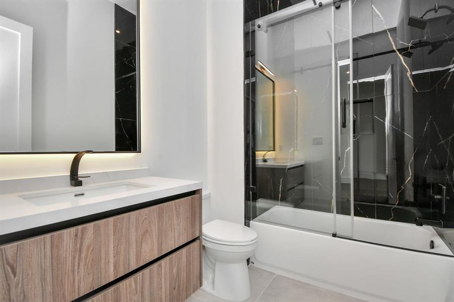 Discover modern elegance in this luxurious bathroom showcasing a sleek tub/shower combo surrounded by contemporary tile. The clean lines and minimalist design create a sophisticated ambiance, perfect for unwinding after a long day.