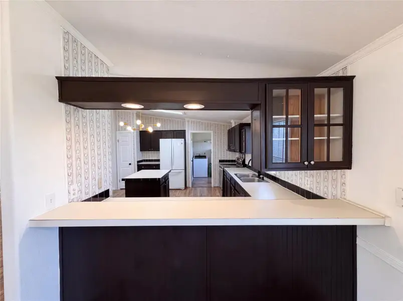 Dark cabinetry and a pass-through bar open this kitchen to the surrounding living areas.