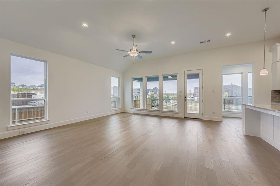 Unfurnished living room with vaulted ceiling, recessed lighting, light wood-style floors, and ceiling fan Unfurnished living room with vaulted ceiling, recessed lighting, light wood-style floors, and ceiling fan