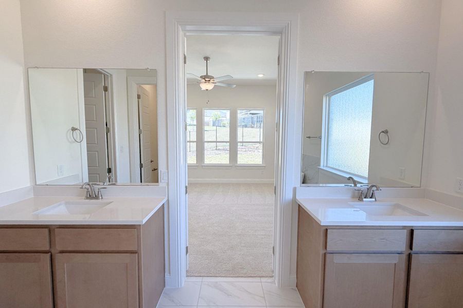 Full bathroom featuring two vanities, ceiling fan, light marble finish floors, and light carpet