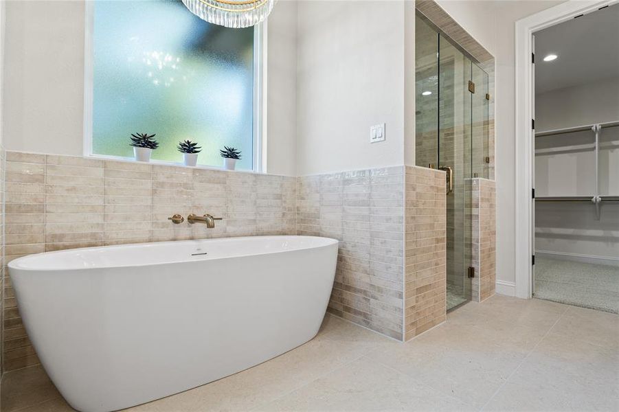 Bathroom with tile walls, a freestanding bath, a shower stall, light tile patterned floors, and a spacious closet