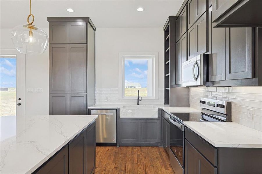 Kitchen featuring sink, stainless steel appliances, decorative light fixtures, and plenty of natural light