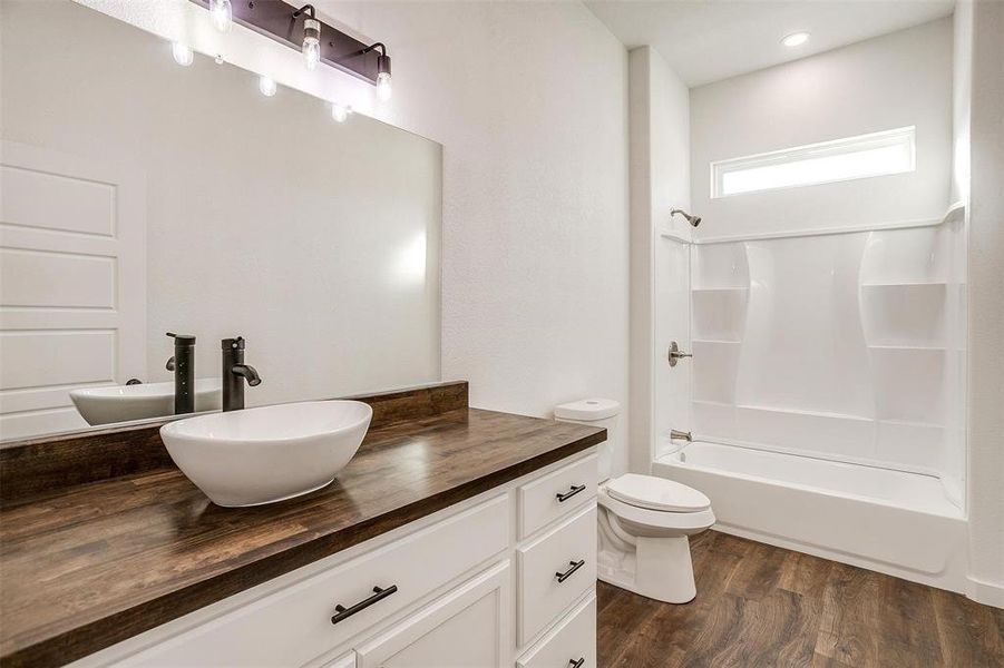 Full bathroom with wood-type flooring, shower / bathing tub combination, vanity, and toilet