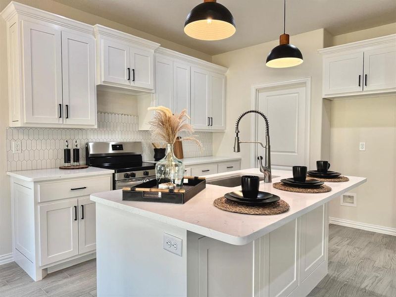 Kitchen with light wood-type flooring, stainless steel range with electric cooktop, white cabinetry, a kitchen island with sink, and backsplash Kitchen with light wood-type flooring, stainless steel range with electric cooktop, white cabinetry, a kitchen island with sink, and backsplash