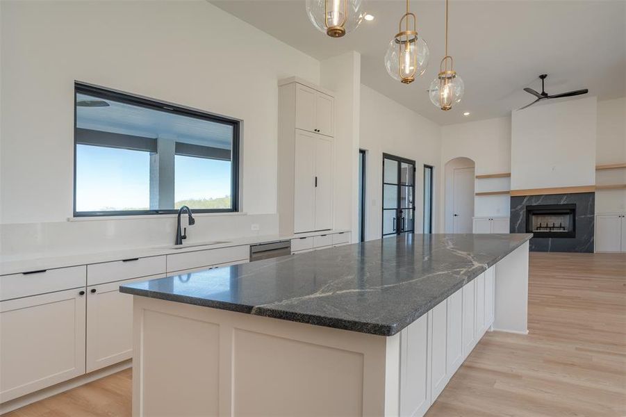 Kitchen with a fireplace, a center island, white cabinetry, and sink