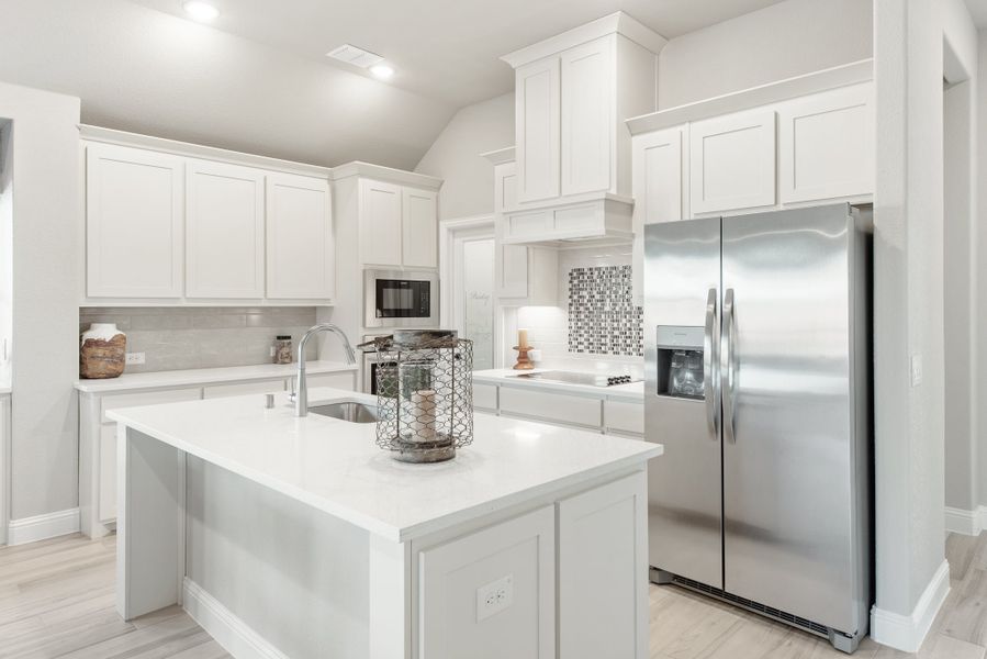 Kitchen with white cabinets, center island with sink, and stainless steel refrigerator