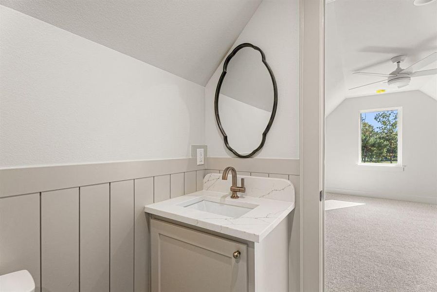 Half bath with vaulted ceiling, vanity, and a ceiling fan