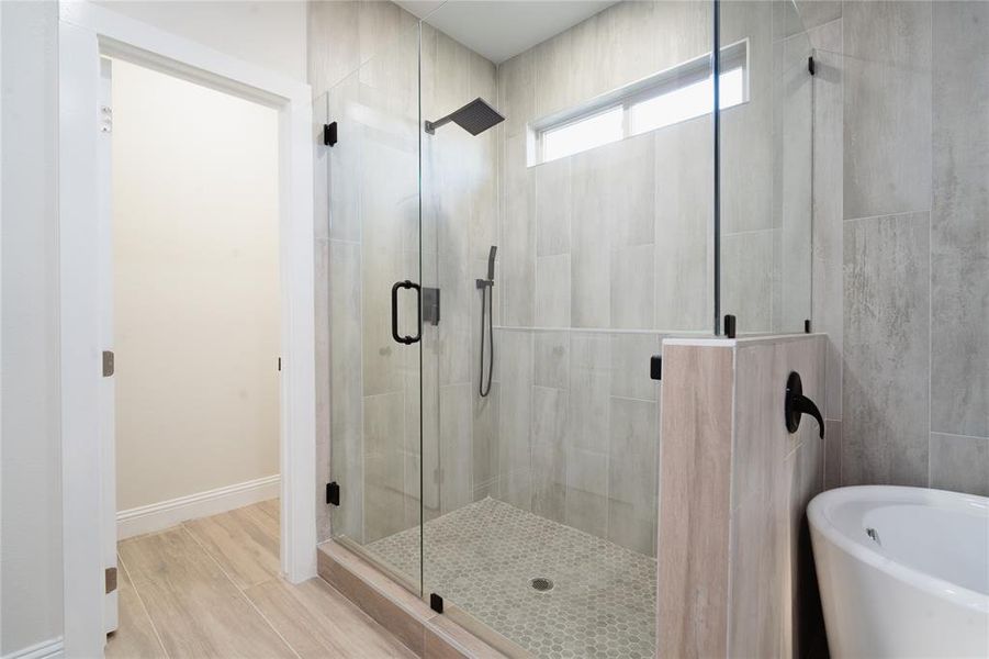 Full bathroom with a stall shower, baseboards, a soaking tub, wood finished floors, and tile walls