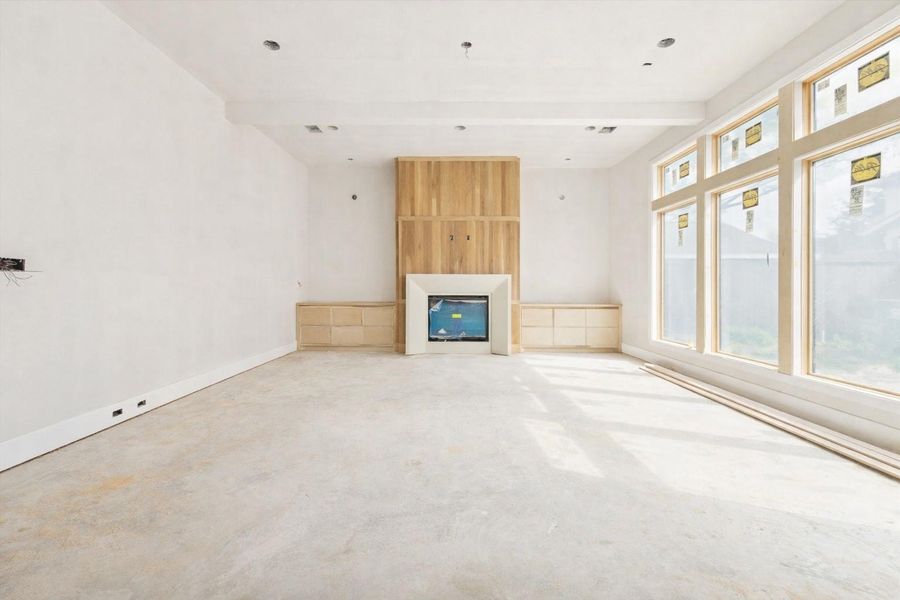 Spacious living room featuring soaring high ceilings and an expansive wall of windows that flood the interior with natural light. This open-concept design centers around a sleek modern fireplace, highlighting premium contemporary finishes and high-end craftsmanship. The large layout offers a seamless flow for entertaining, emphasizing clean lines and a sophisticated modern aesthetic in this stunning new construction. Spacious living room featuring soaring high ceilings and an expansive wall of windows that flood the interior with natural light. This open-concept design centers around a sleek modern fireplace, highlighting premium contemporary finishes and high-end craftsmanship. The large layout offers a seamless flow for entertaining, emphasizing clean lines and a sophisticated modern aesthetic in this stunning new construction.