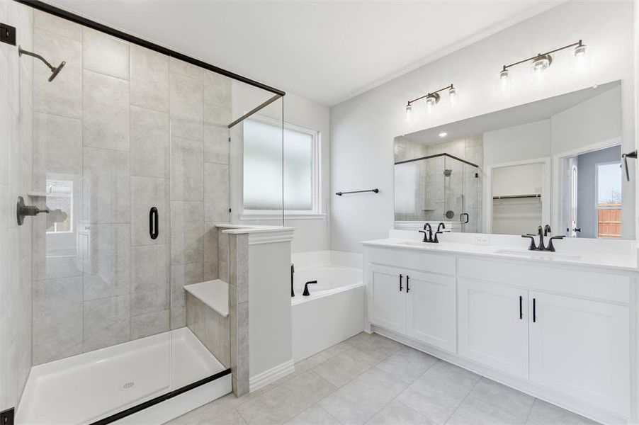 Full bathroom featuring double vanity, a bath, a spacious closet, a shower stall, and light tile patterned floors