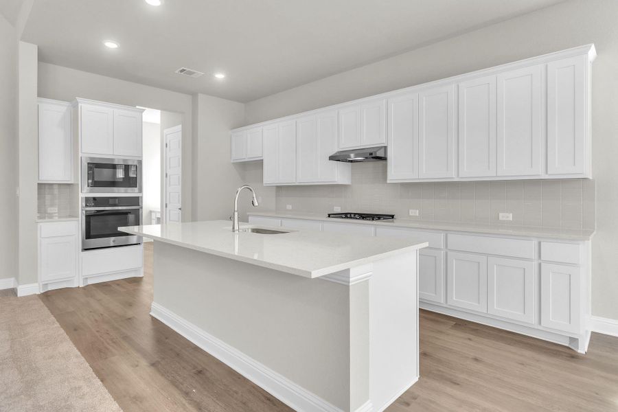 Kitchen featuring light wood-type flooring, visible vents, a sink, under cabinet range hood, and stainless steel appliances Kitchen featuring light wood-type flooring, visible vents, a sink, under cabinet range hood, and stainless steel appliances