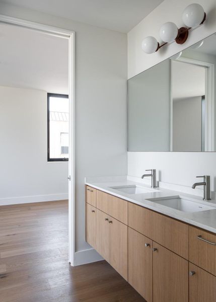 Bathroom with double vanity and dark wood-style flooring