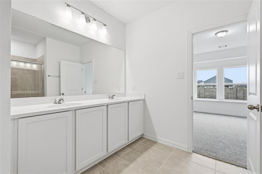 Full bathroom featuring a stall shower, double vanity, light tile patterned floors, and light carpet