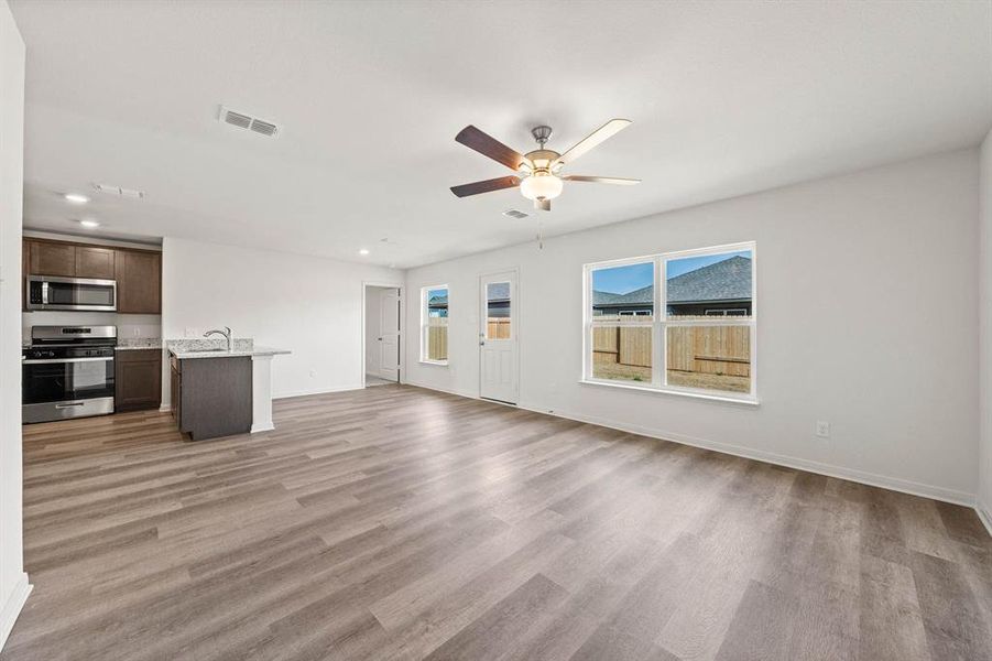 Unfurnished living room featuring sink, light wood-type flooring, and ceiling fan