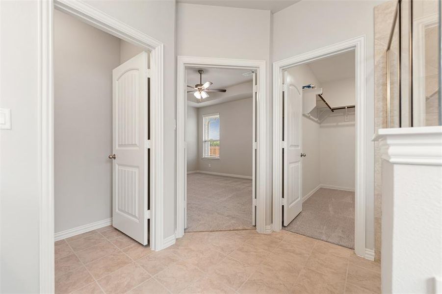 Hallway featuring light tile patterned floors and light carpet Hallway featuring light tile patterned floors and light carpet