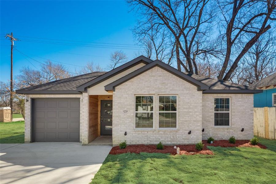 Ranch-style home featuring a garage and a front lawn