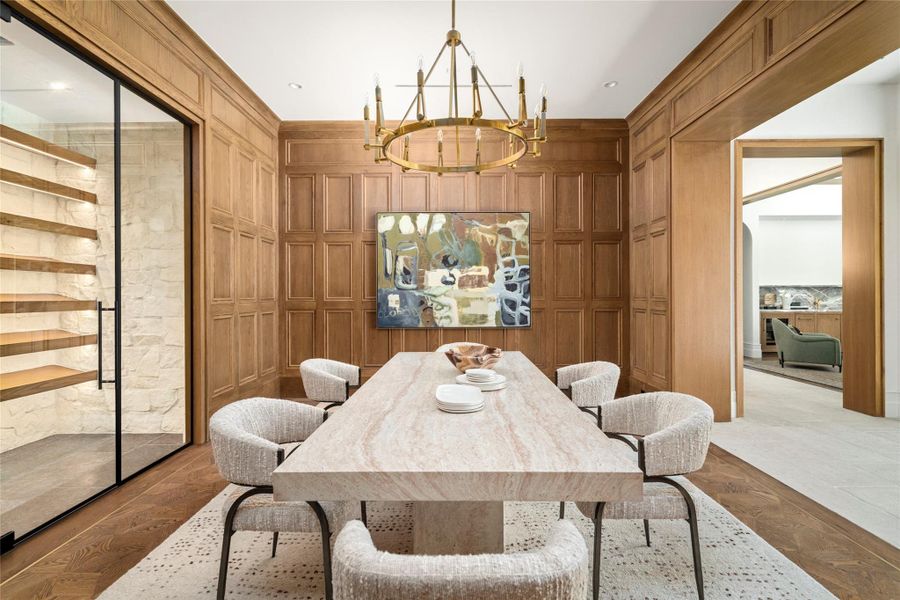 The formal dining room is wrapped in custom rift-sawn white oak millwork, creating a rich, tailored backdrop for entertaining. Versailles-style white oak parquet flooring and a hand-rubbed antique brass chandelier complete the sophisticated setting, with direct access to the glass-enclosed, climate-controlled wine room. The formal dining room is wrapped in custom rift-sawn white oak millwork, creating a rich, tailored backdrop for entertaining. Versailles-style white oak parquet flooring and a hand-rubbed antique brass chandelier complete the sophisticated setting, with direct access to the glass-enclosed, climate-controlled wine room.