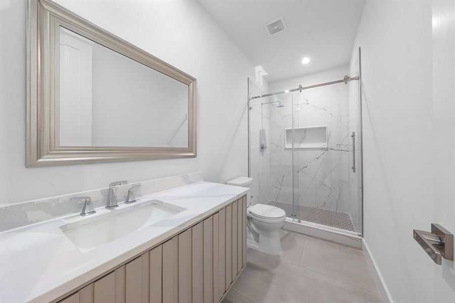 Bathroom with a marble finish shower, vanity, light tile patterned floors, and recessed lighting Bathroom with a marble finish shower, vanity, light tile patterned floors, and recessed lighting