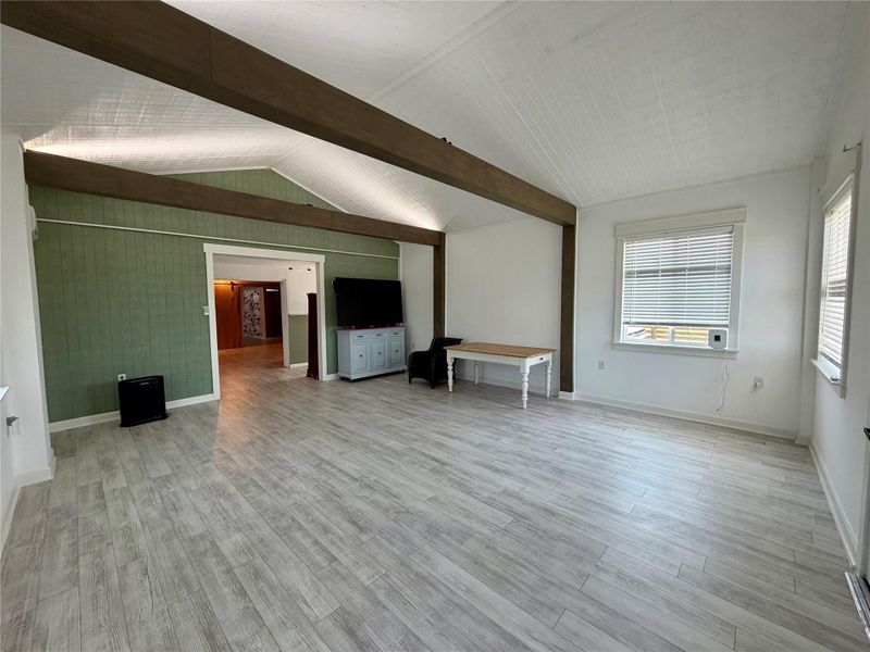 A spacious common area boasts wood-look flooring and architectural beam accents.