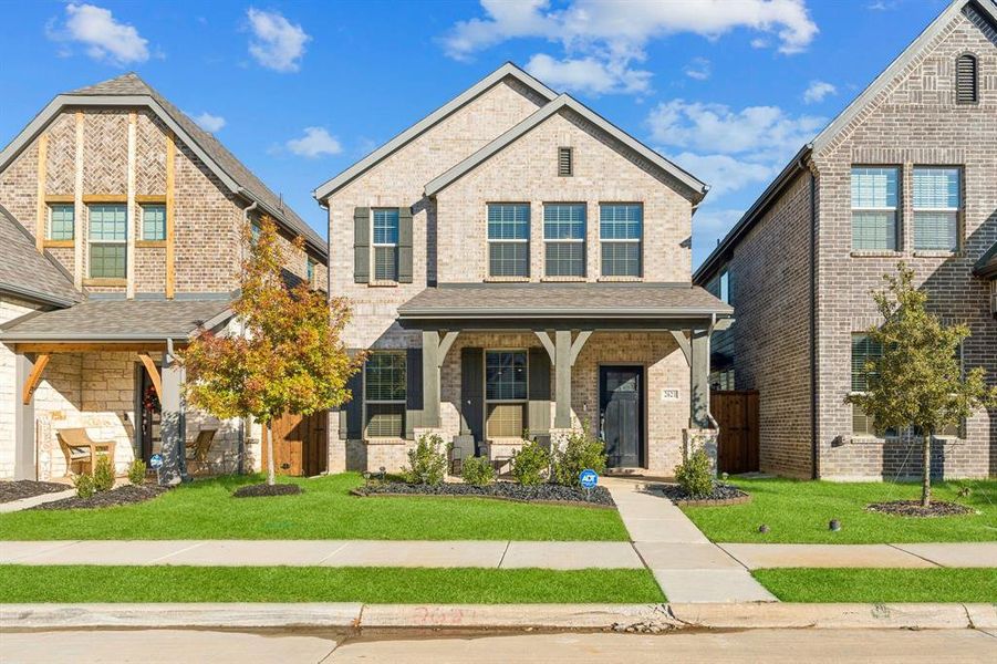 View of front of house featuring a porch, a front lawn, and brick siding