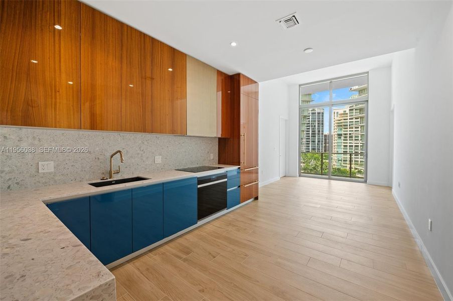 Open-concept kitchen and living area with designer cabinetry, premium appliances, and seamless indoor-outdoor flow to balcony—ideal for entertaining.