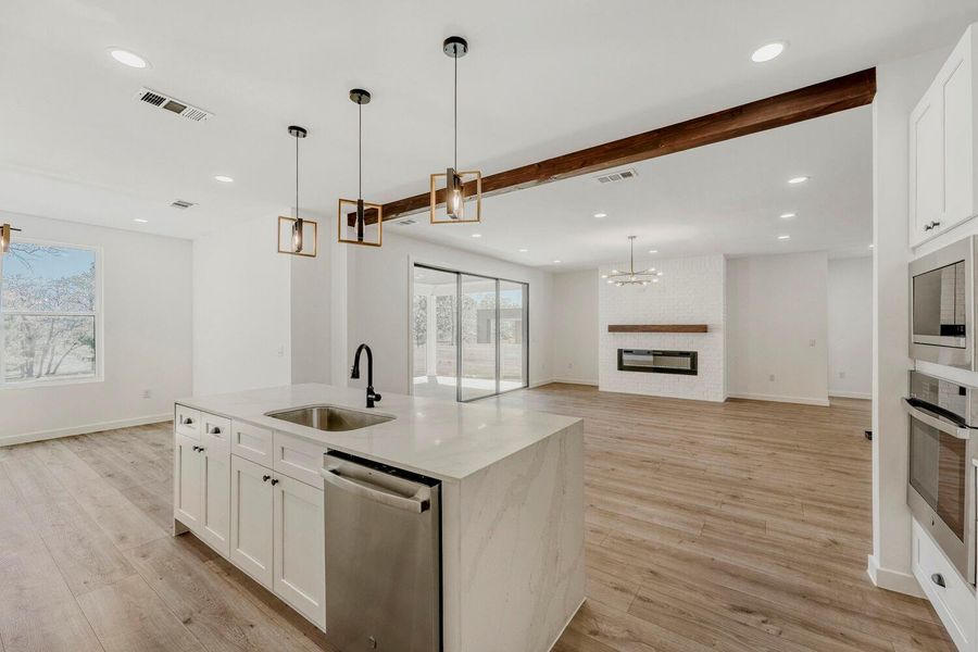 Kitchen featuring white cabinetry, open floor plan, a fireplace, a chandelier, and stainless steel appliances