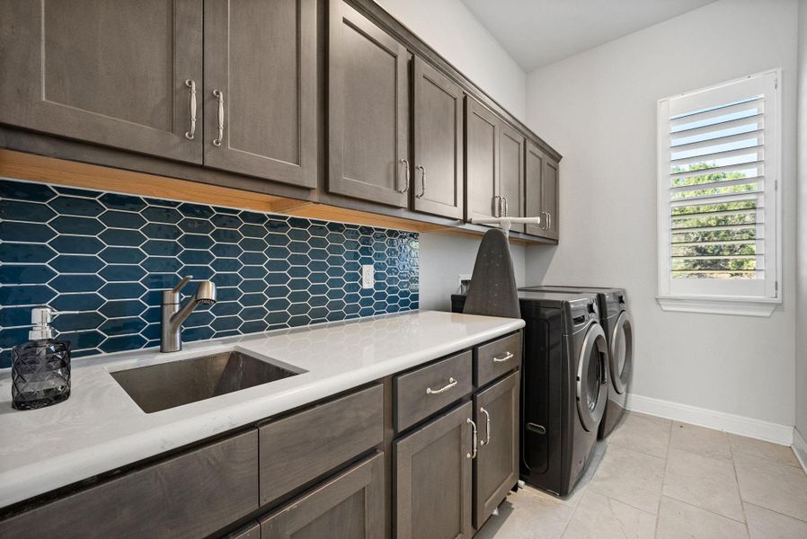 Laundry area featuring washer and clothes dryer, cabinet space, and light tile patterned floors