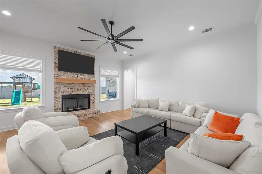 Living area featuring crown molding, light wood-style floors, recessed lighting, ceiling fan, and a fireplace Living area featuring crown molding, light wood-style floors, recessed lighting, ceiling fan, and a fireplace