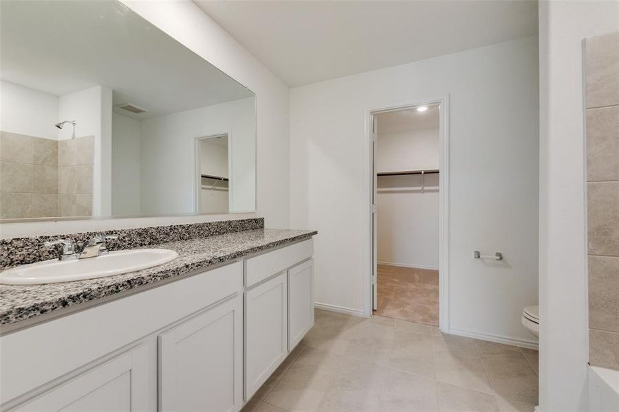 Bathroom with tile patterned flooring, a shower, vanity, and toilet